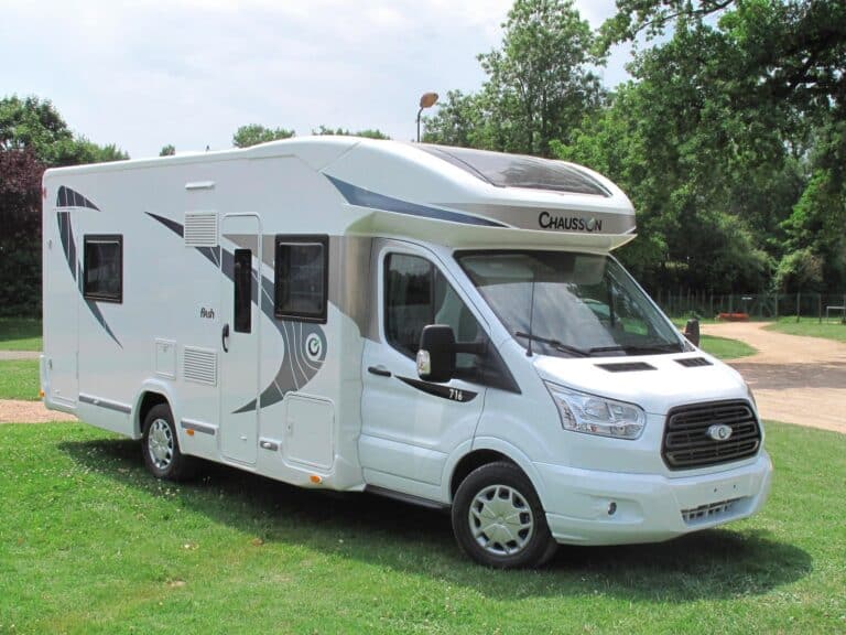 Camping-car Chausson blanc moderne garé dans un parc.