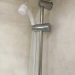 Douchette et support métallique dans salle de bains.