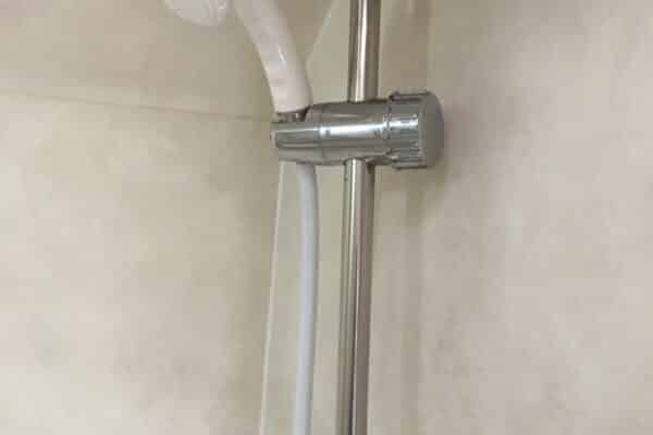 Soffione e supporto metallico in bagno.