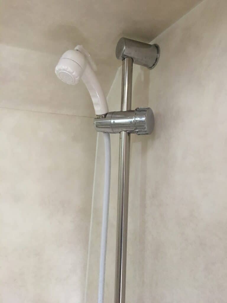 Douchette et support métallique dans salle de bains.