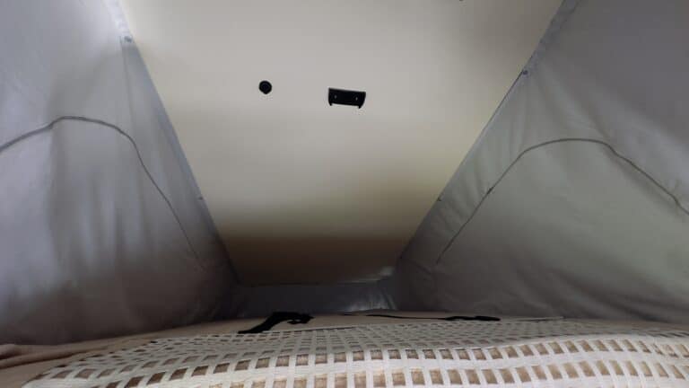 Intérieur de tente avec matelas et plafond équipé.