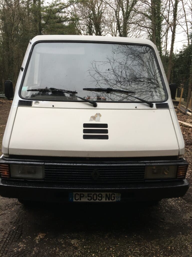 Camionnette blanche Renault stationnée en forêt.