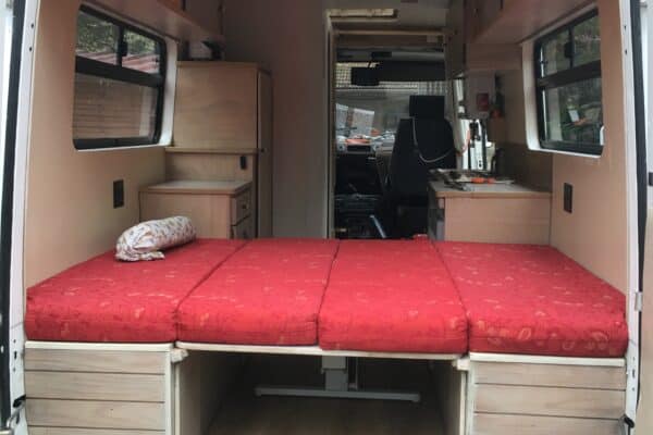 Interno dell'fourgonnette con letto rosso.