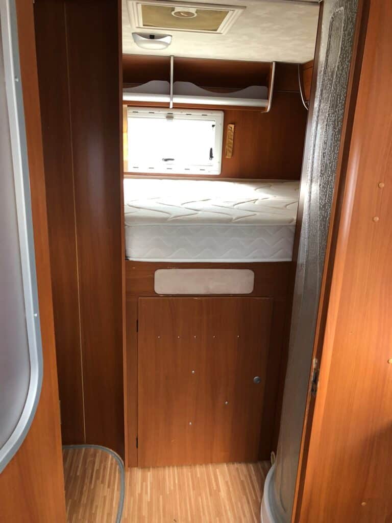 Intérieur de caravane avec lit confortable et rangements.