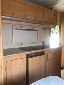 Intérieur de caravane avec cuisine compacte en bois.