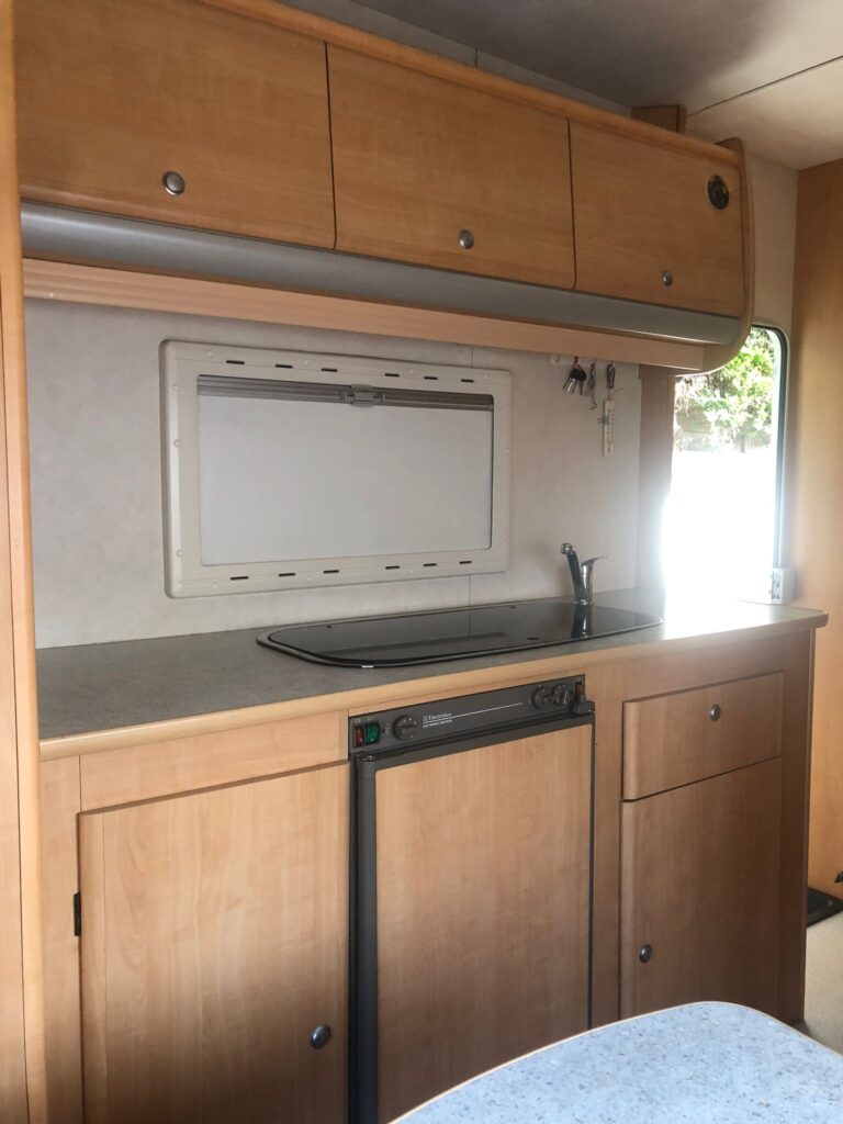 Intérieur de caravane avec cuisine compacte en bois.