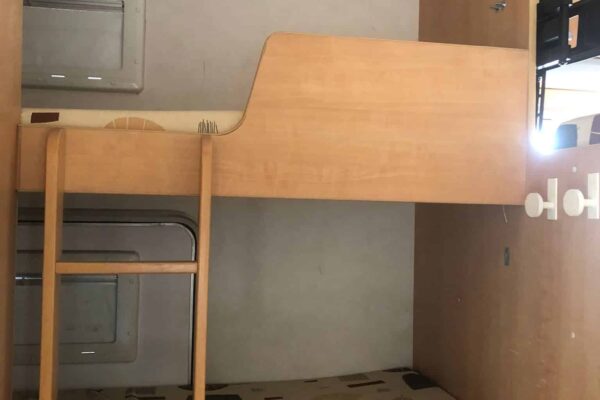 Intérieur de caravane avec lits superposés et meubles en bois.