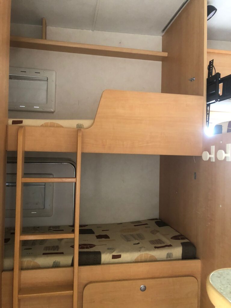 Intérieur de caravane avec lits superposés et meubles en bois.