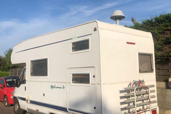 Camping-car blanc garé sous le soleil.