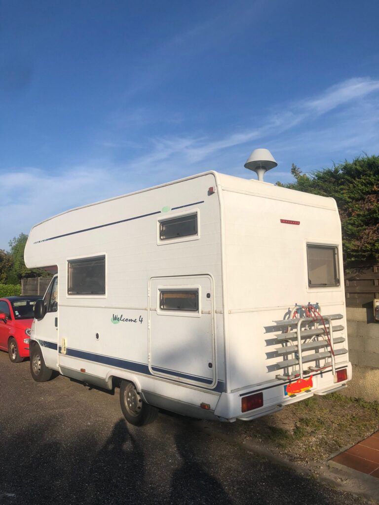 Camping-car blanc garé sous le soleil.