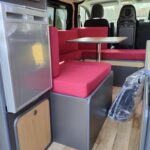 Intérieur de camping-car moderne avec cuisine et sièges rouges.
