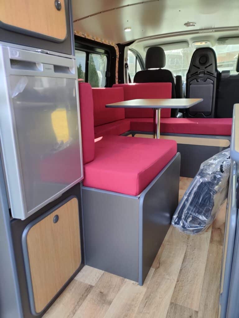 Intérieur de camping-car moderne avec cuisine et sièges rouges.