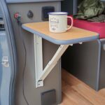 Intérieur de van aménagé avec table rabattable et tasse.