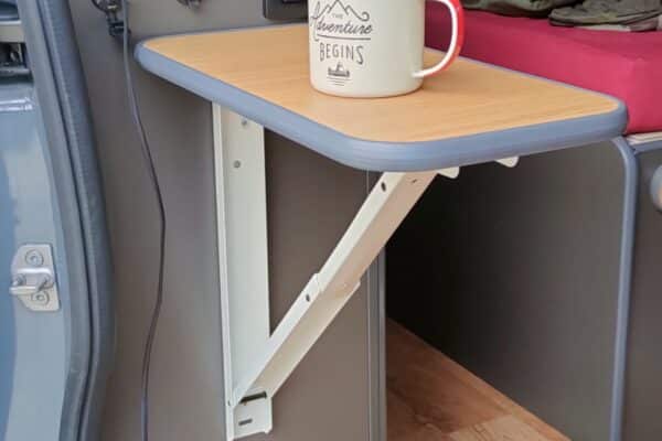 Intérieur de van aménagé avec table rabattable et tasse.