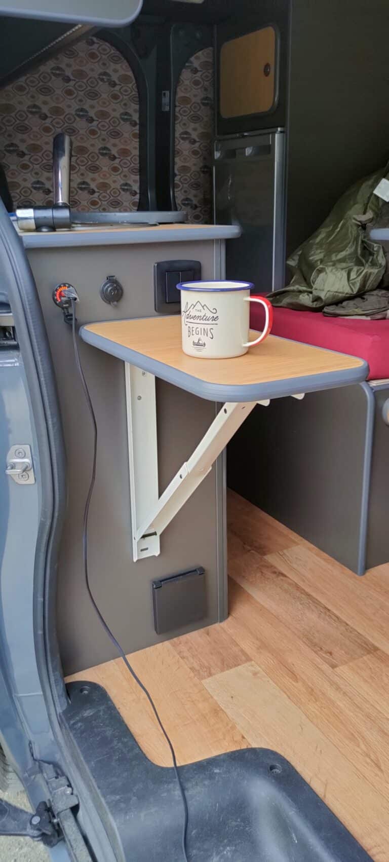 Intérieur de van aménagé avec table rabattable et tasse.