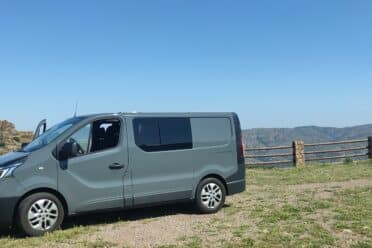 Fourgonnette grise, paysage montagneux, ciel clair.