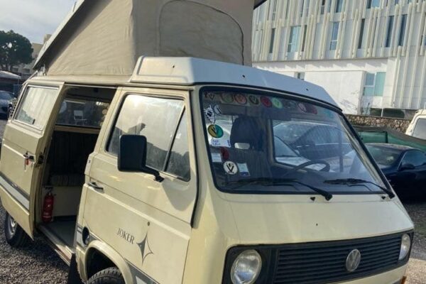Fourgon VW beige avec toit relevable, parking.