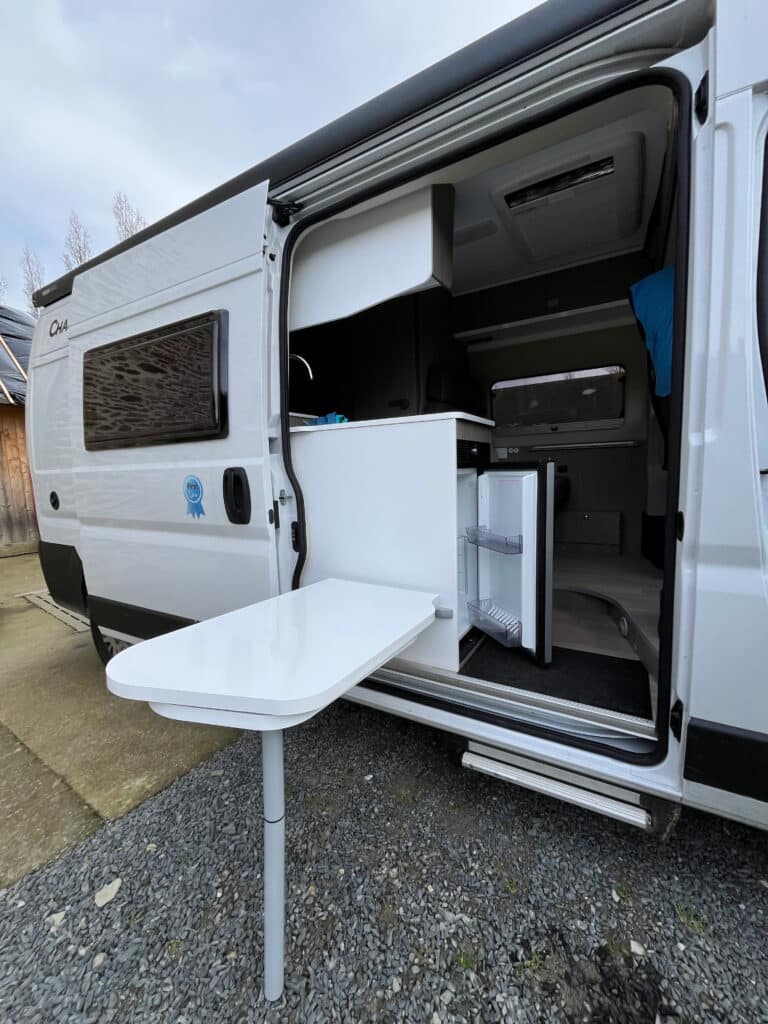 Caravane moderne avec intérieur visible et table extérieure