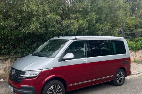 Monospace rouge garé près d'arbres verts