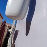 Vue partielle d'un camion blanc, logo visible, ciel bleu