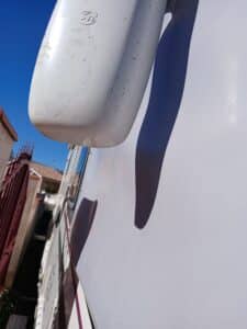 Vue partielle d'un camion blanc, logo visible, ciel bleu