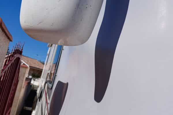 Vue partielle d'un camion blanc, logo visible, ciel bleu