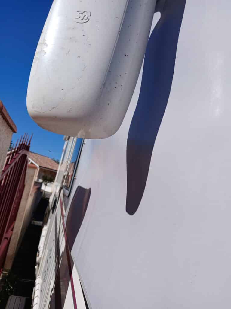 Vue partielle d'un camion blanc, logo visible, ciel bleu