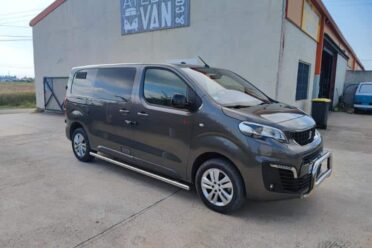 Fourgonnette grise stationnée devant un bâtiment industriel