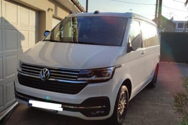 Fourgonnette blanche Volkswagen garée devant garage