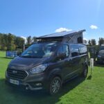 Fourgon aménagé Ford sur herbe verte, ciel bleu