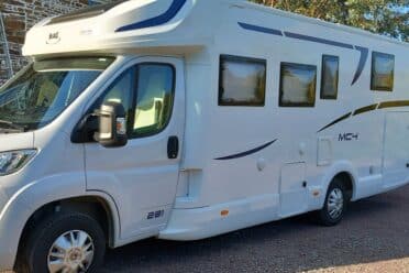 Camping-car blanc stationné devant un mur en briques