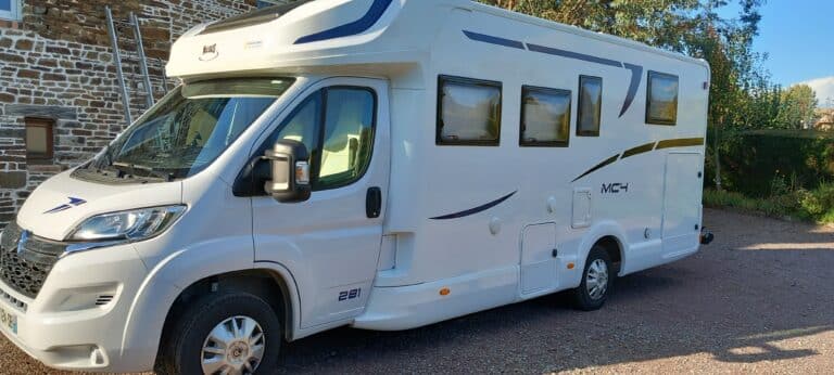 Camping-car blanc stationné devant un mur en briques