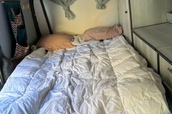 Gemütliches Interieur von Wohnmobil mit weichem Bett.