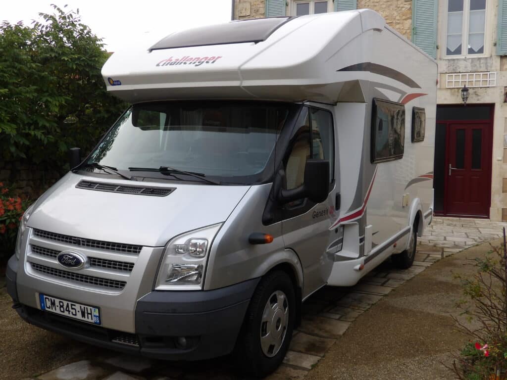Camping-car gris devant une maison