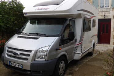 Camping-car gris devant une maison