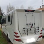 Camping-car Rapido blanc avec porte-vélos arrière.