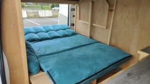 Intérieur de camionnette aménagée avec lit turquoise