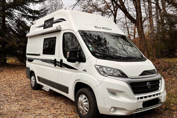 Camping-car blanc en forêt automnale
