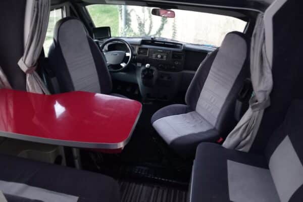 Innenausstattung von Wohnmobil mit Sitzen und rotem Tisch