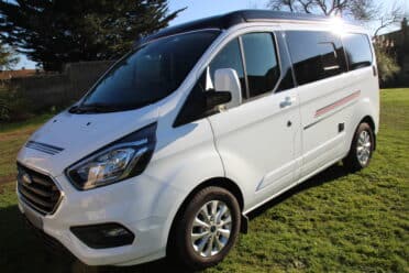 Fourgonnette blanche moderne stationnée sur l'herbe