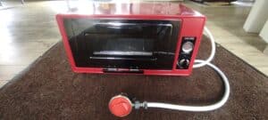 Four électrique portable rouge sur un tapis