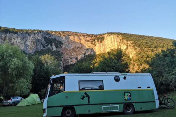 Wohnmobil grün geparkt vor Felsklippen