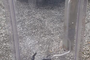 Pare-brise transparent posé sur un sol de gravier