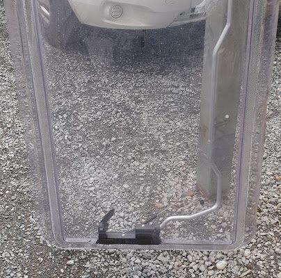 Pare-brise transparent posé sur un sol de gravier