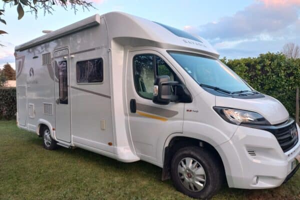 Camping-car Bavaria garé devant des arbustes