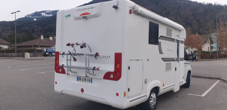 Camping-car blanc stationné dans un parking de montagne