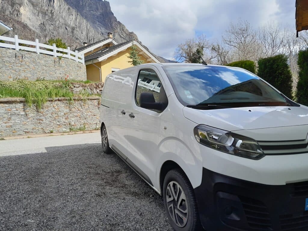 Fourgon blanc stationné devant maison de montagne