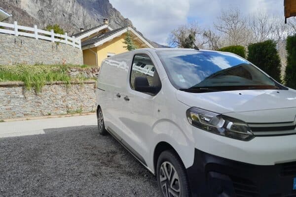 Fourgon blanc stationné devant maison de montagne