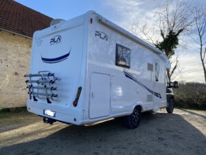 Camping-car moderne garé devant vieille bâtisse