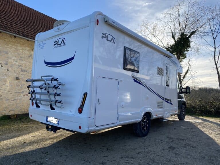 Camping-car moderne garé devant vieille bâtisse